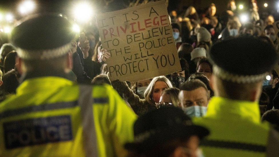 A woman holds up a placard as people gather in Clapham Common