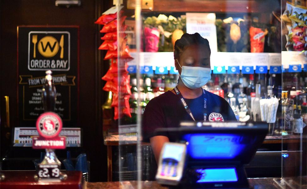 A bar worker uses a till behind a pub bar