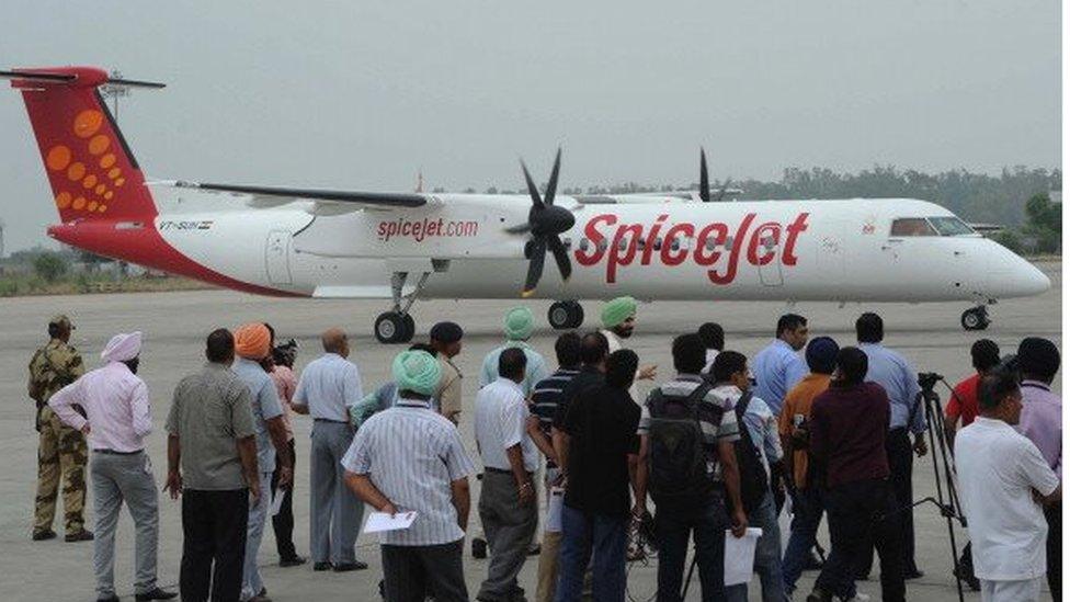 Indian airport officials watch a Spice jet flight arrive at Raja Sansi International