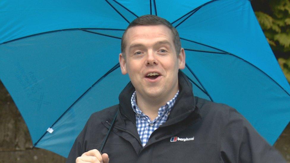 Douglas Ross holds an umbrella