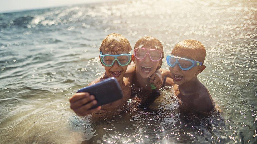 Kids-in-sea-using-phone.