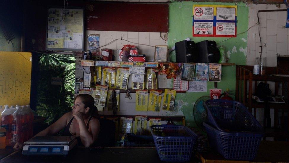 An employee of a supermarket waits during a power cut in Santa Teresa, Miranda State, Venezuela