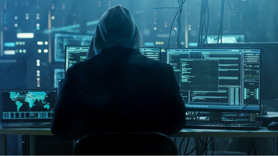 Criminal hacker with multiple computer screens