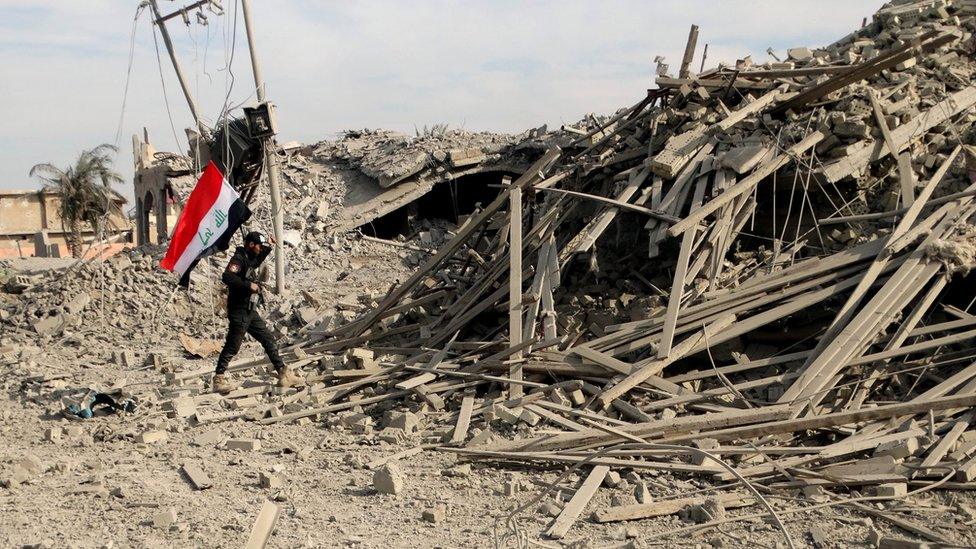 An Iraqi soldier holds a national flag in Ramadi, on 27 December, 2015