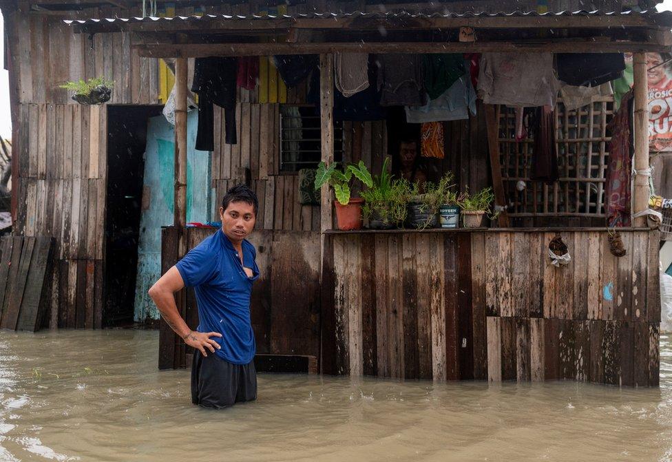 A man stands in front of a flooded house caused by monsoon rains and the recent typhoon Doksuri, in Balagtas, Bulacan province, Philippines, July 29, 2023.