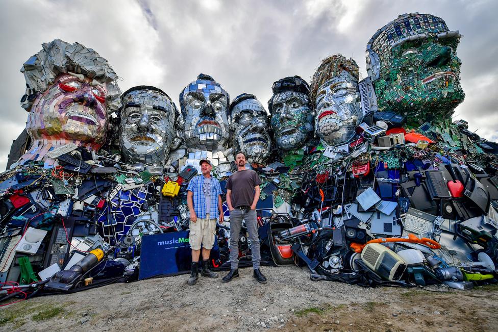 Artists Alex Wreckage, left, and Joe Rush, right, stand in front of their artwork Mount Trashmore, on the beach near Gwithian