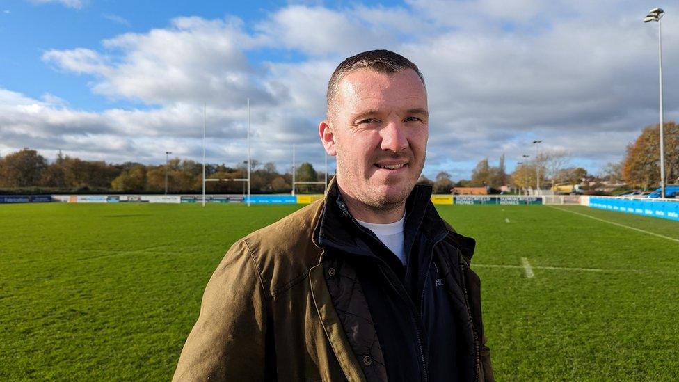 Tom Foley looking at the camera standing on an empty rugby pitch