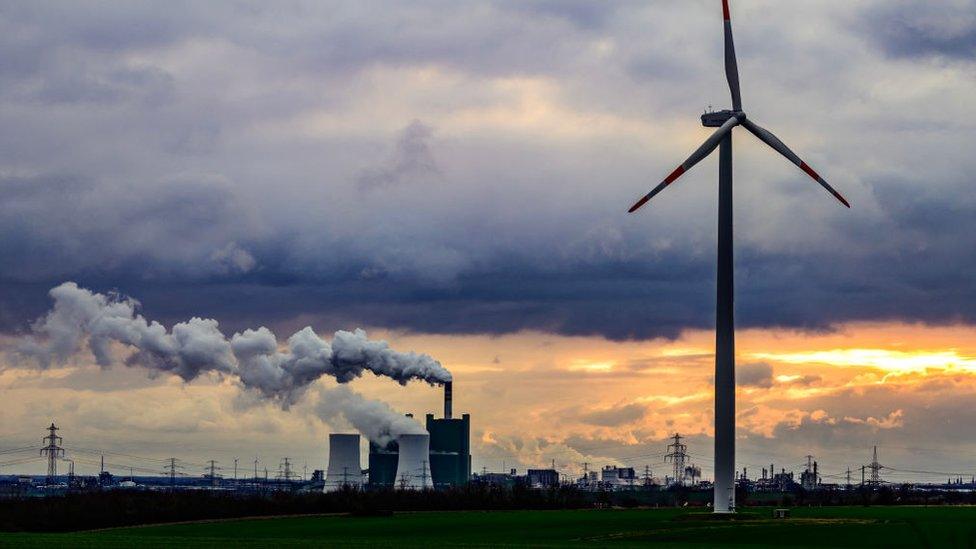 wind turbine in front of coal power plant