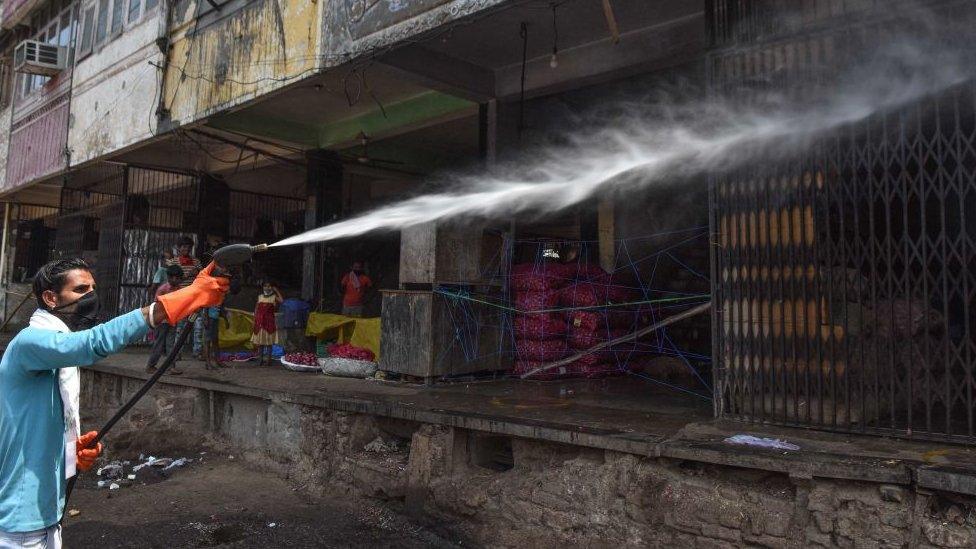 A sanitation worker spraying disinfectant over shops in Azadpur Mandi, on May 1, 2020 in New Delhi, India.