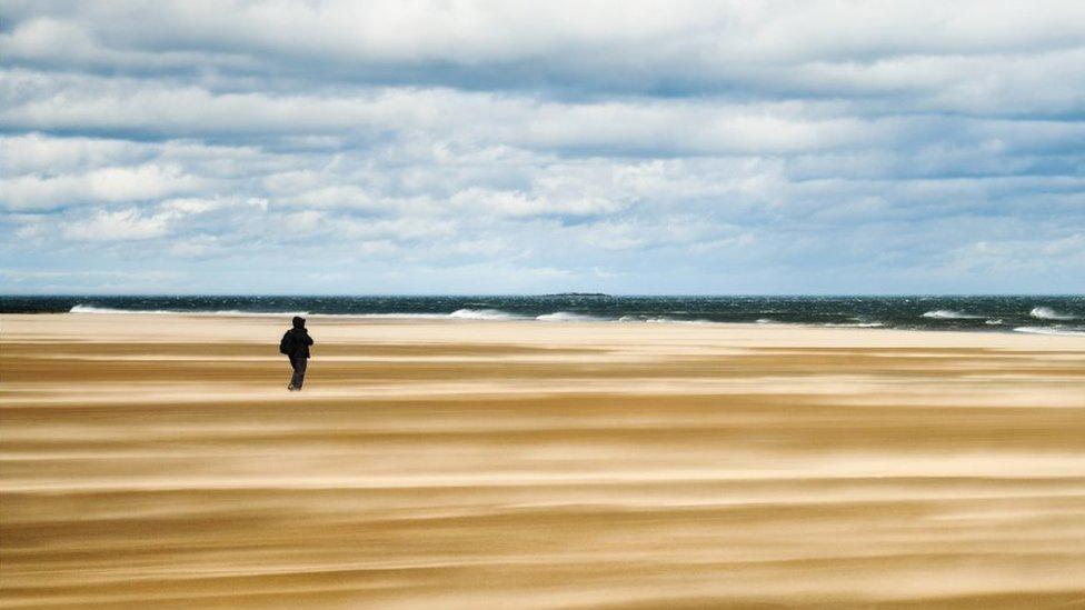 Walker on a beach in Northumberland