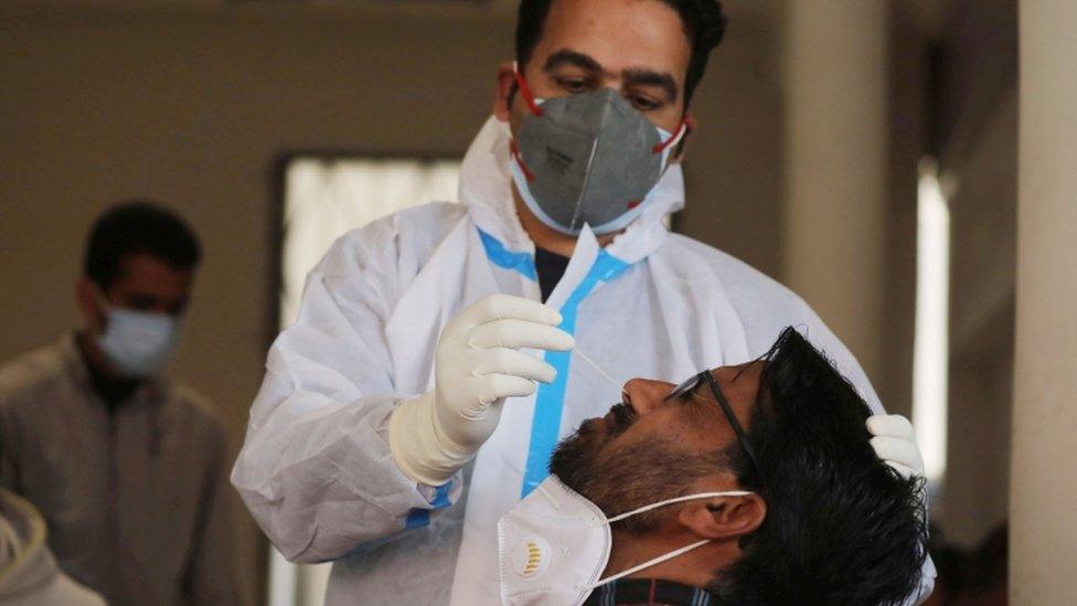 A health worker takes a nasal swab sample from a man in India