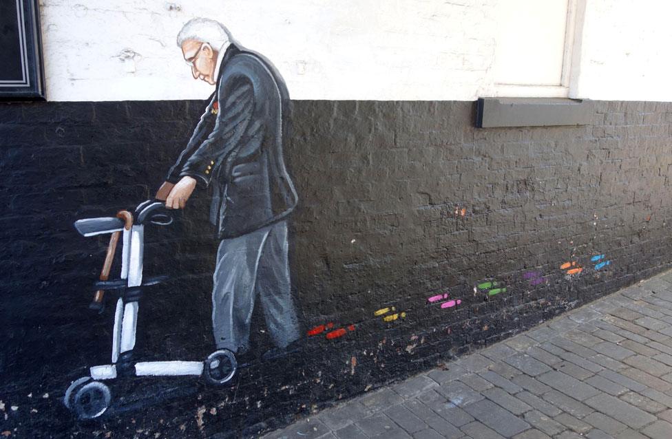 A mural showing Capt Sir Tom Moore walking with his walking frame