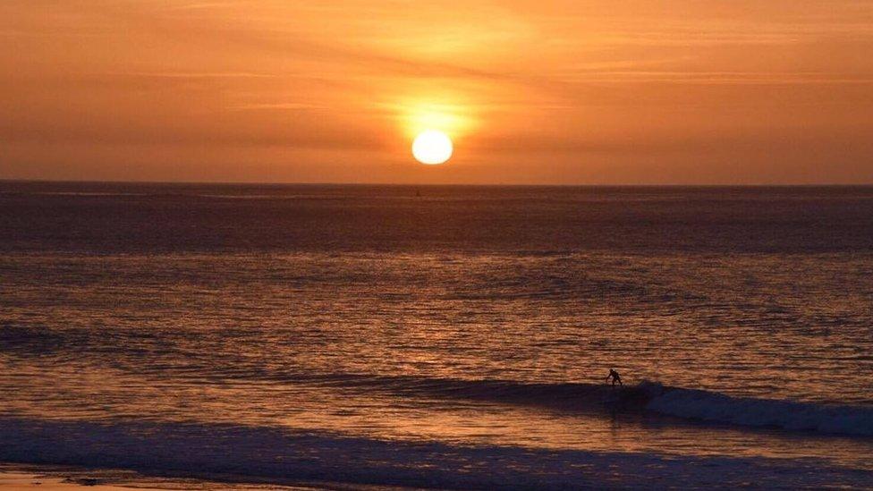 The sun rises over Langland Bay, Swansea, as a surfer takes to the water. Picture by Mark de'Boer Lloyd