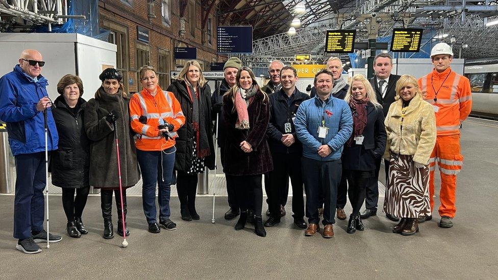 15 people gathered on a train platform