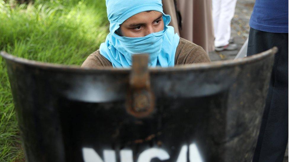 A protestor sits behind a homemade shield next to National University of Nicaragua (UNAN) after clashes in Managua, Nicaragua, June 23, 2018.