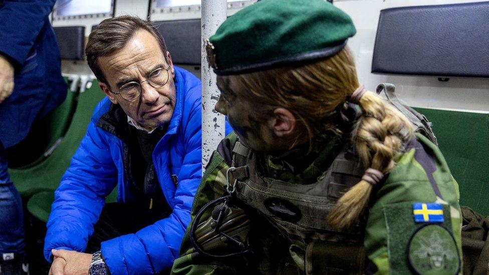 Swedish Prime Minister Ulf Kristersson (left) speaks to a Swedish soldier during a visit to a naval base. Photo: February 2024