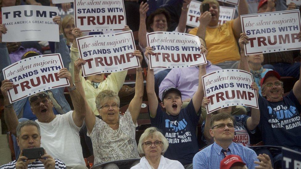 Donald Trump's fans hold up signs at a rally.