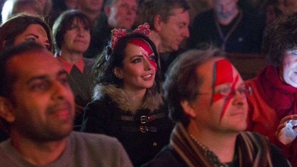 Fans with their faces painted listen to bands play during a tribute evening for British music legend David Bowie