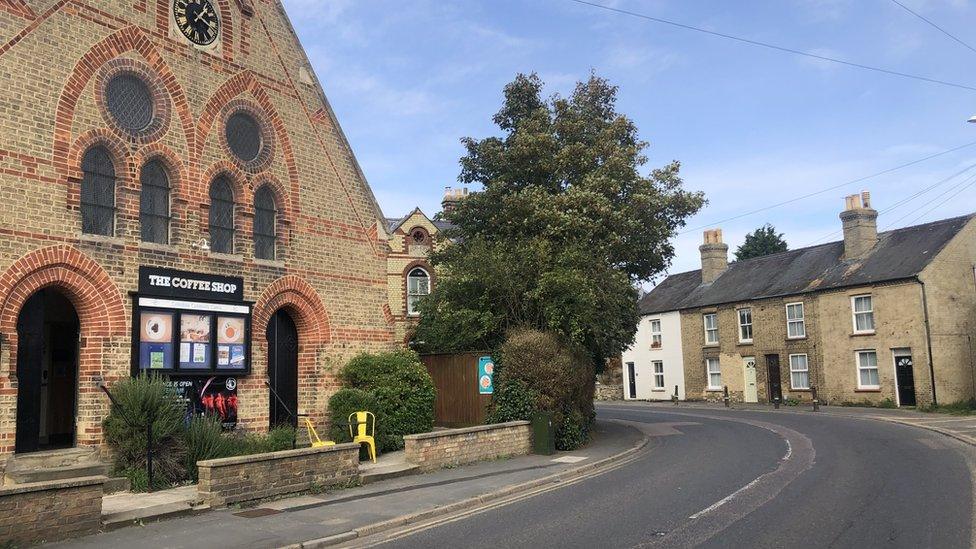 Road in Cottenham going round a tight bend heading left next to a coffee shop and terrace houses