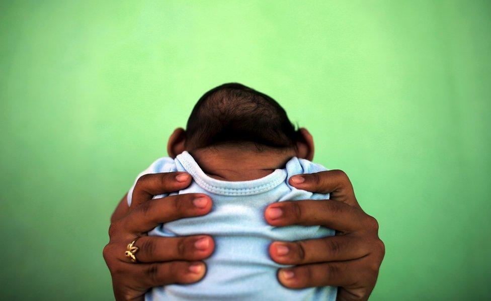 Jackeline, 26, holds her son who is four months old and born with microcephaly, in front of their house in Olinda, near Recife, Brazil, 11 February 2016.