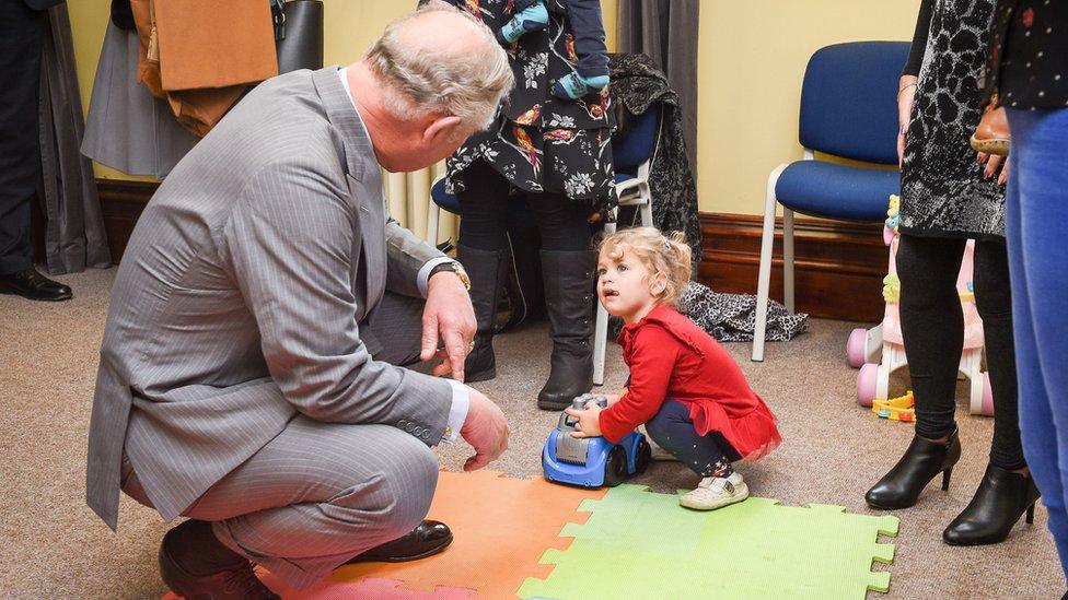 The Prince of Wales asks to play with a toy car that Rosie Jewell, aged 23 months, from Caerphilly, is playing with, during his visit to the Caerphilly Miners Community Centre