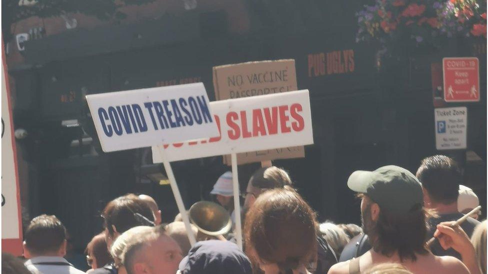 Two signs being held up at the demonstration on Saturday in Belfast, with one sign reading 'Covid treason'