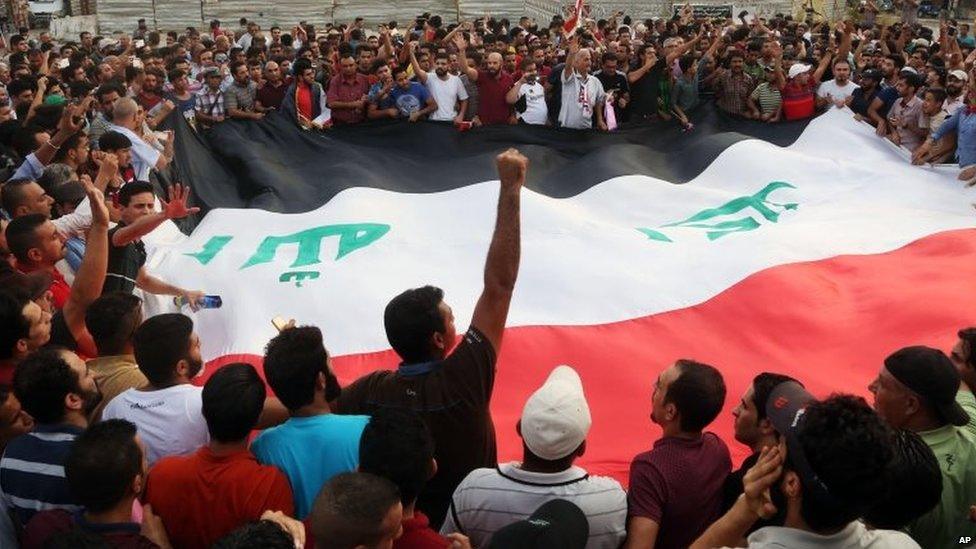 Protesters chant anti-Iraqi government slogans as they carry a large national flag during a protest against against corruption and the lack of government services in Tahrir Square in central Baghdad, Iraq, Friday, 31 July 2015