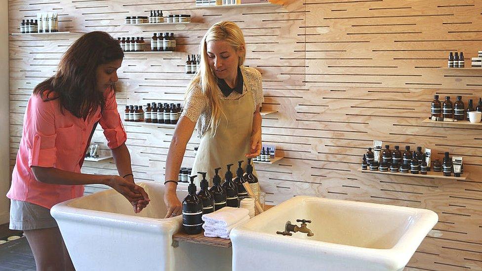 An Aesop consultant helps a customer test a product at a store in Venice.