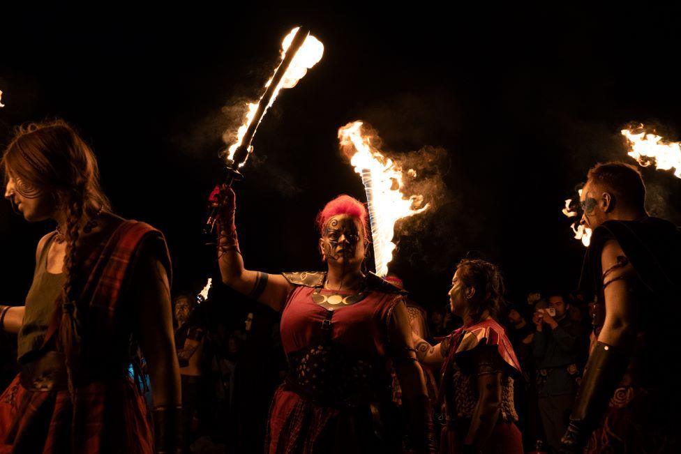 A group of performers dressed as Celtic warriors holding fire torches.