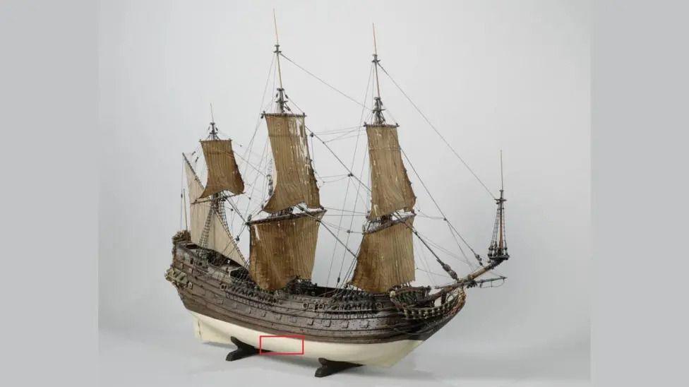 A model of an old trading ship, with part of the hull highlighted in a red box
