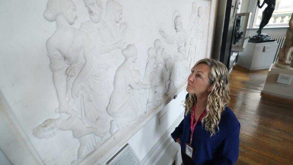 Assistant curator Alex Patterson examines a relief panel at the Walker Art Gallery which features a member of the Sandbach family