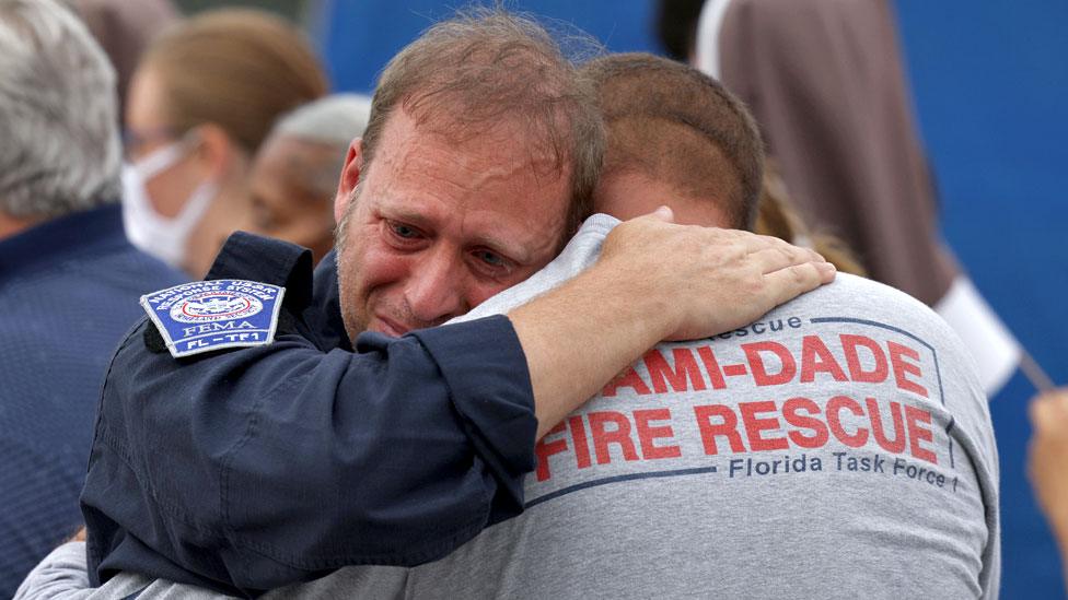 Rescue workers with the Miami Dade Fire Rescue embrace after a moment of silence near the memorial site for victims of the collapsed 12-story Champlain Towers South condo building on July 07, 2021 in Surfside, Florida