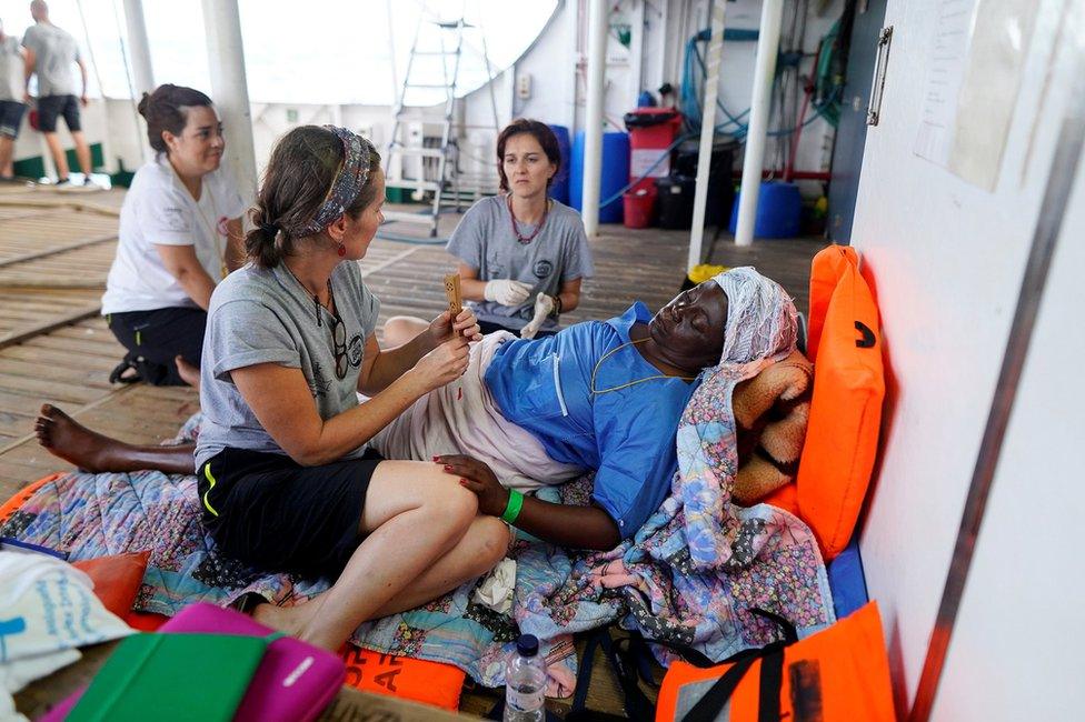 NGO Proactiva Open Arms members sit with Josepha from Cameroon onboard of NGO Proactiva Open Arms rescue boat in central Mediterranean Sea