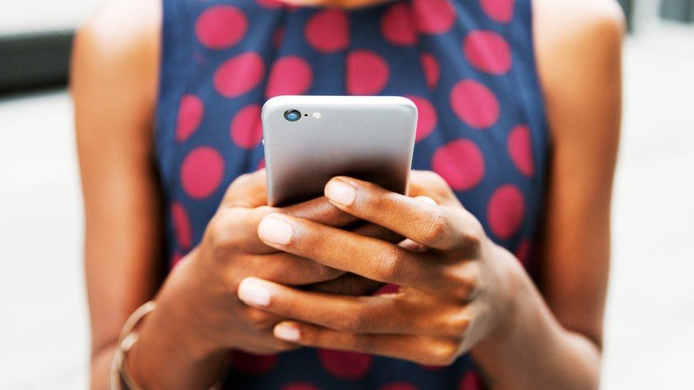 A woman holds a phone in close-up