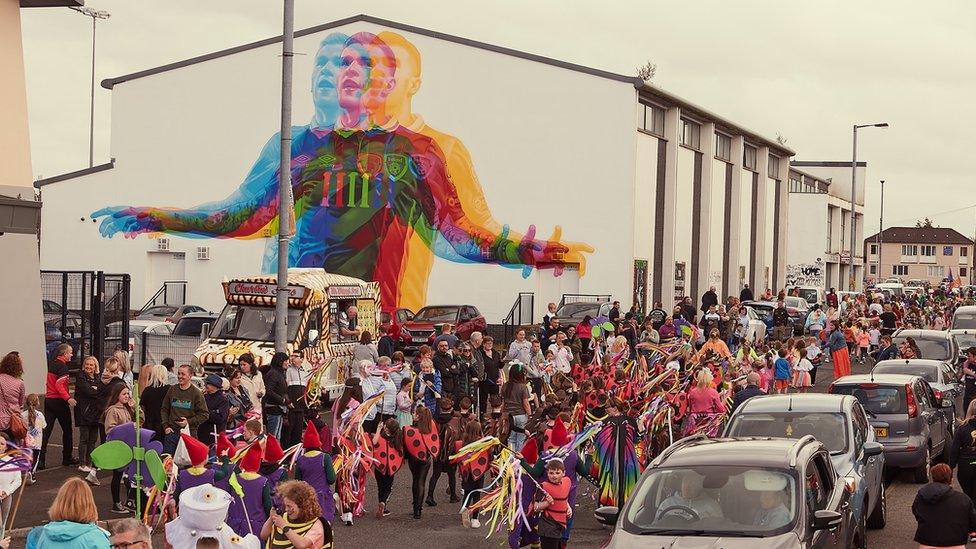 parade passing James mcClean mural in Derry's creggan estate