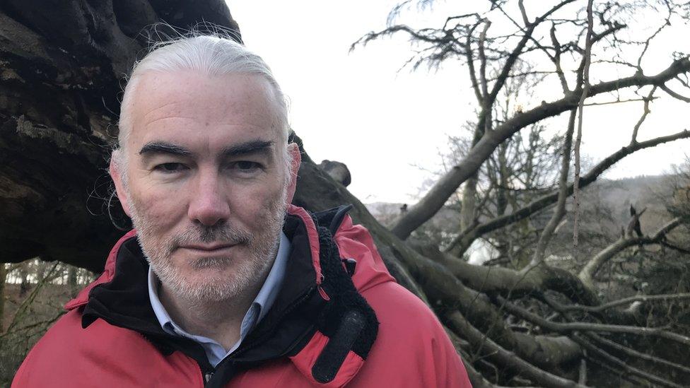 John Moffat next to the Crested Beech champion tree, blown over by Arwen