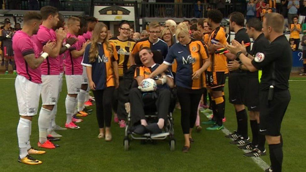 Simon Dobbin and his family on the pitch surrounded by Cambridge United and Southend United players