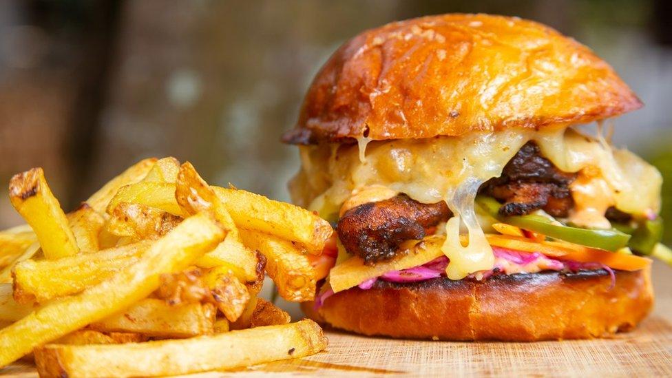 A burger bun next to a portion of chips