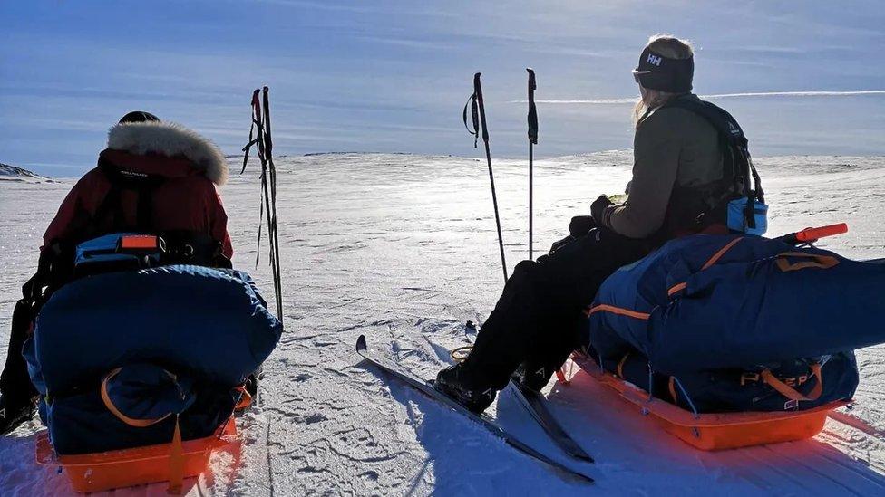 Georgina Gilbert and Rebecca Openshaw-Rowe on snow in cross country skiers sitting on their sledges