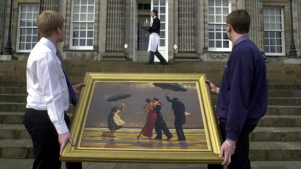 Two men carry Jack Vettriano's The Singing Butler outside Hopetoun House, where it was being auctioned in 2004. At the top of steps in the background a butler is carrying a tray with glasses and a bottle.