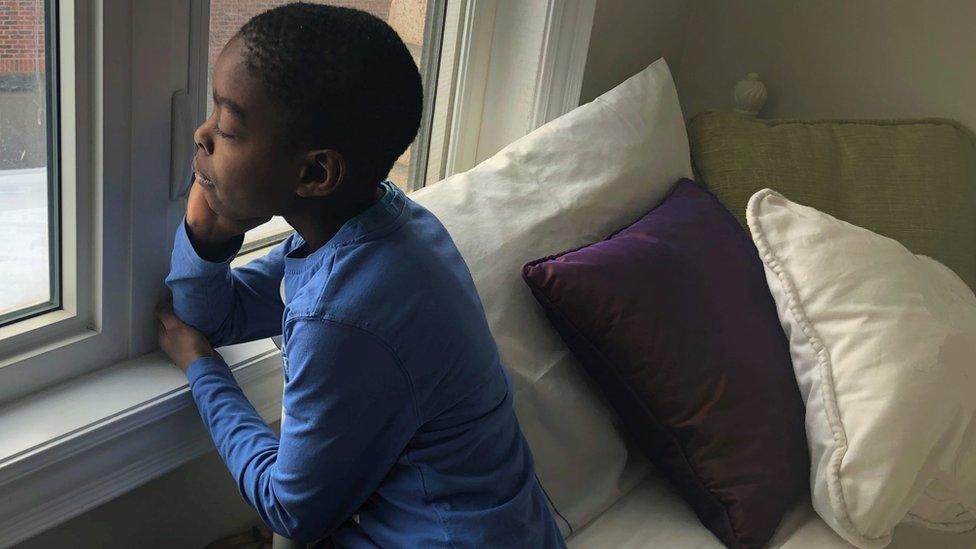 Boy on bed looks out of window