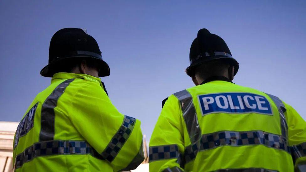 Two police officers stand with their backs to the camera