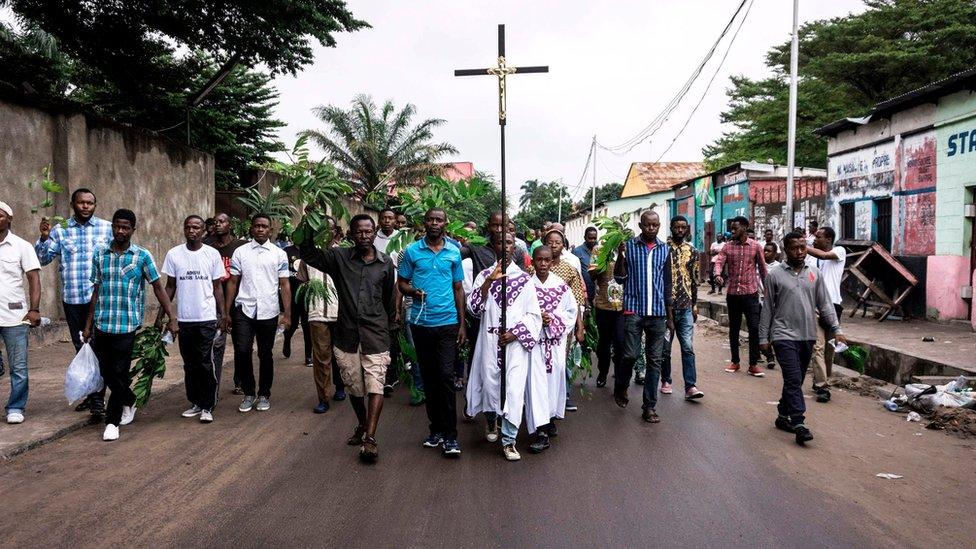 A man holds a cross as he takes part, with a group of Catholic faithfuls, in a demonstration outside the St Francois De Sales Church on 25 February 2018