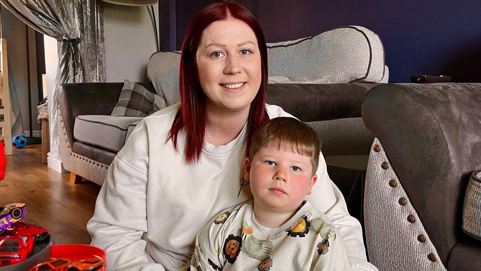 Rebecca and son Raif, five, in their sitting room with a sofa behind