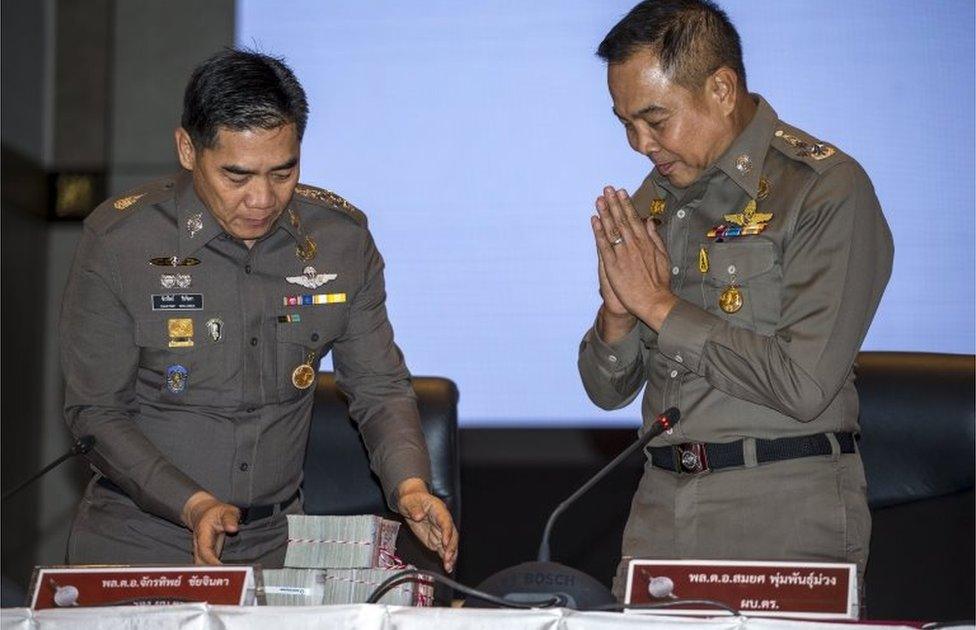 Thai national police chief Somyot Poompanmuang (R) gestures as he hands over a reward to deputy police chief Chakthip Chaijinda before a news conference about the Bangkok blast which killed 20 people, including foreigners, at the Royal Thai Police headquarters in central Bangkok, Thailand, September 28, 2015.