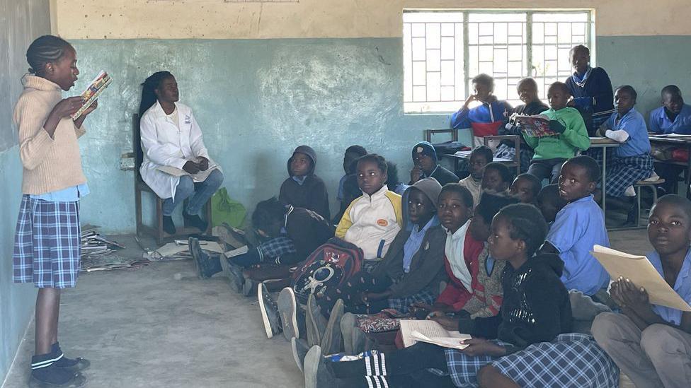 A pupil standing at the front of the class reading something out