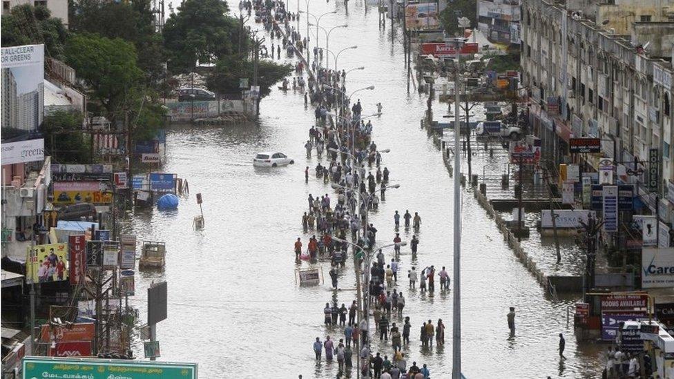 People walk through a flooded street in Chennai, India, Thursday, Dec. 3, 2015