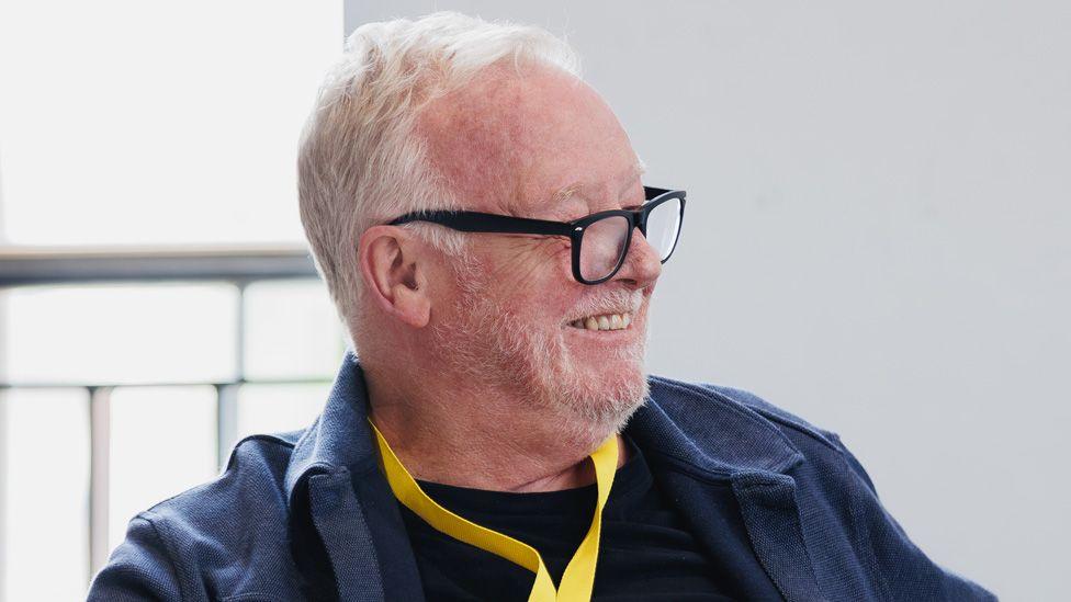 Head and shoulders of Les Dennis wearing black glasses in the rehearsal room for Twelfth Night