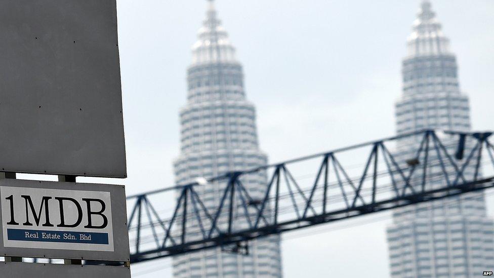 1MDB logo and Malaysia's Petronas Towers in the background