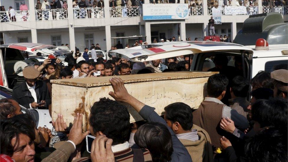 Mourners surround a coffin